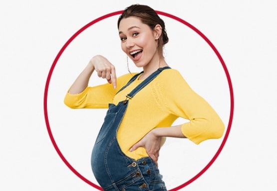 Happy young pregnant woman wearing yellow jumper and pointing to her tummy